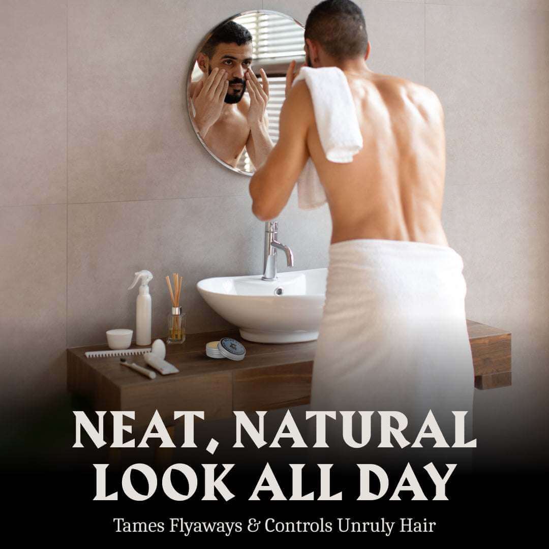 Man in a bathroom with a towel around his waist, looking at himself in the mirror.