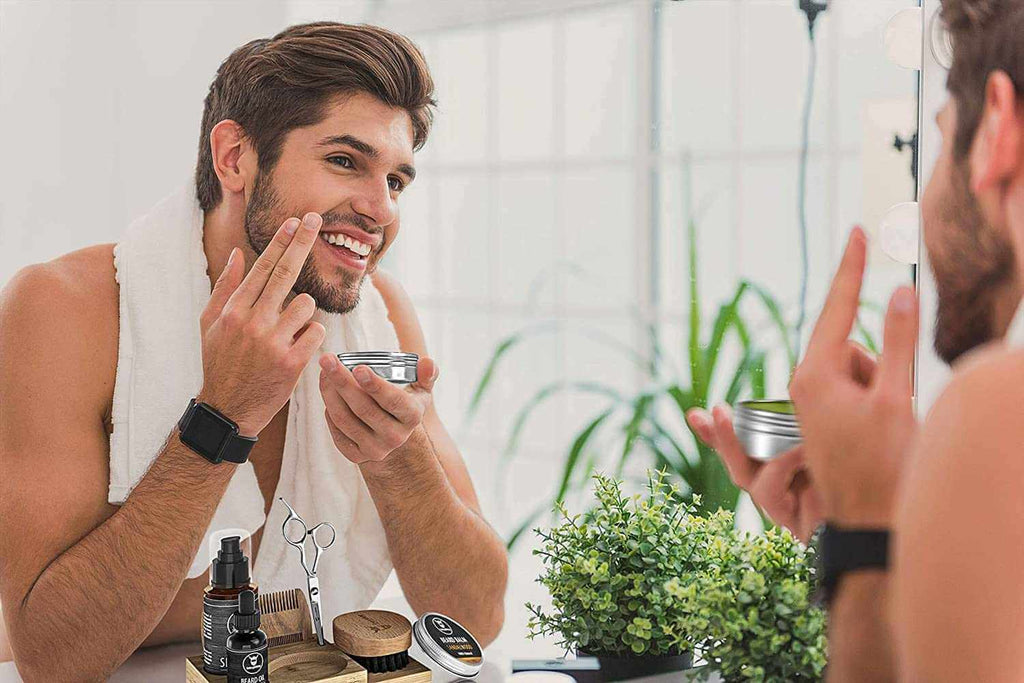 Man applying cream to his face in front of a mirror with a plant in the background